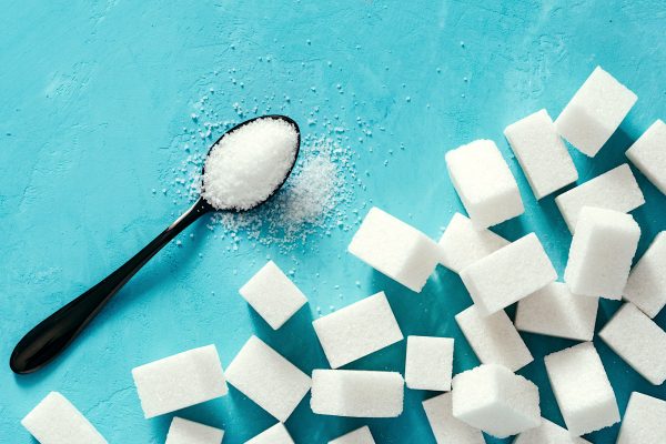 Top view of white sugar cubes on blue concrete background