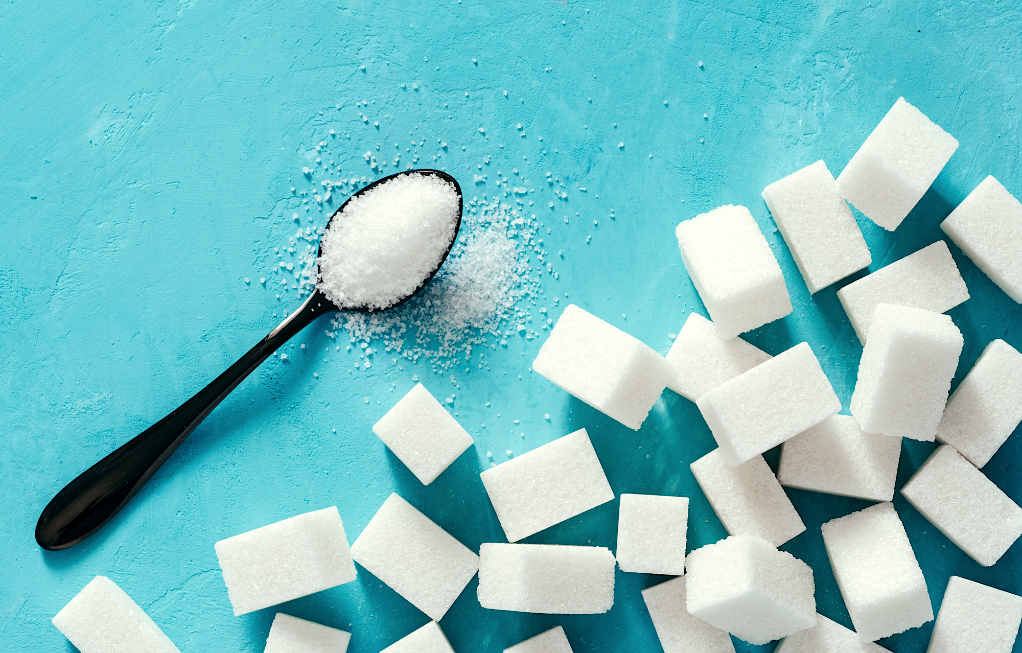 Top view of white sugar cubes on blue concrete background